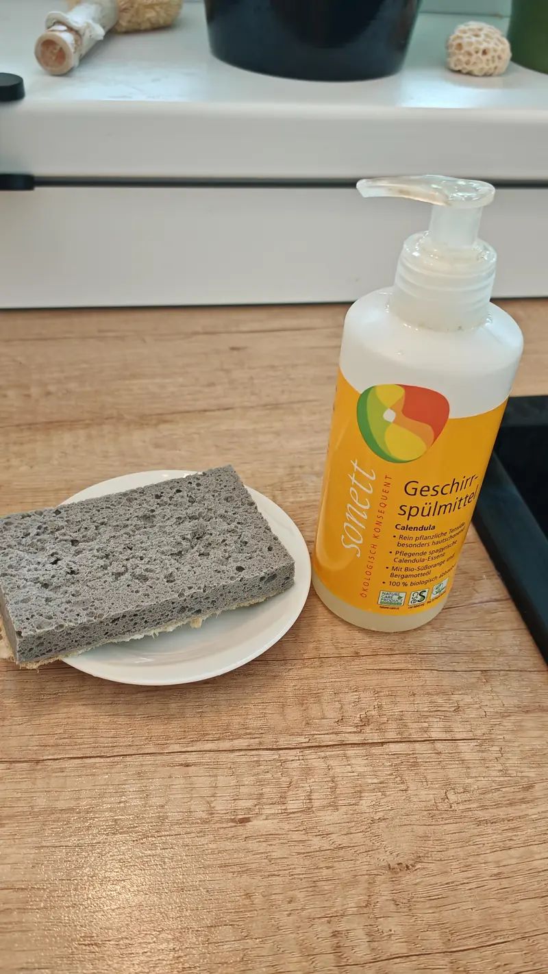 Plant-based dish soap and a natural sponge on a saucer